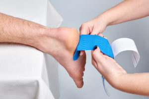 Orthopedic doctor treating a patient using peroneal tendonitis taping methods.