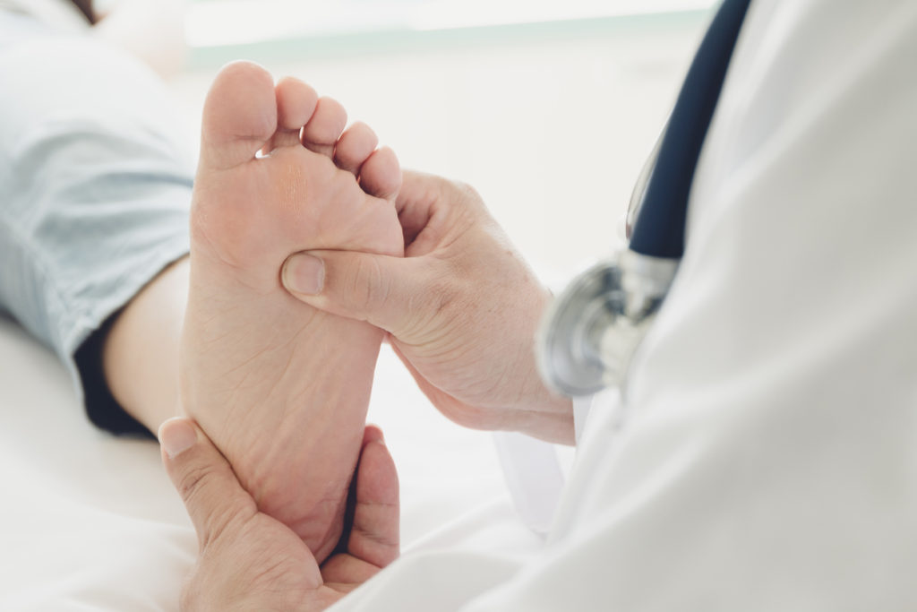 Doctor in a medical clinic checking a patient's foot showing signs of plantar plate tear.